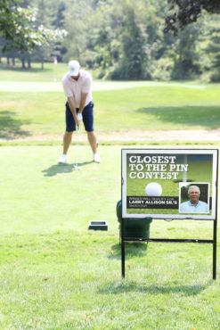 golfer taking a put with closest to the pin sign